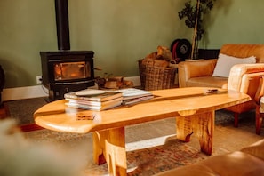 A cozy living room with a wooden coffee table, a sofa, a wicker basket, and a fireplace.