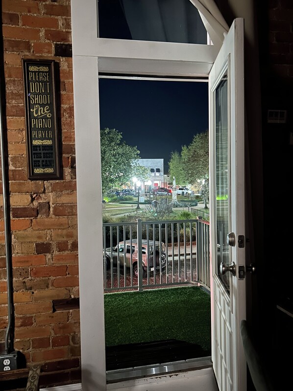 A door with a sign on the wall and a view of a parking lot at night.