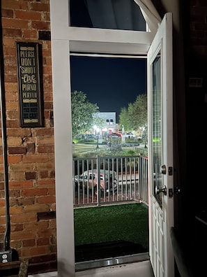 A door with a sign on the wall and a view of a parking lot at night.