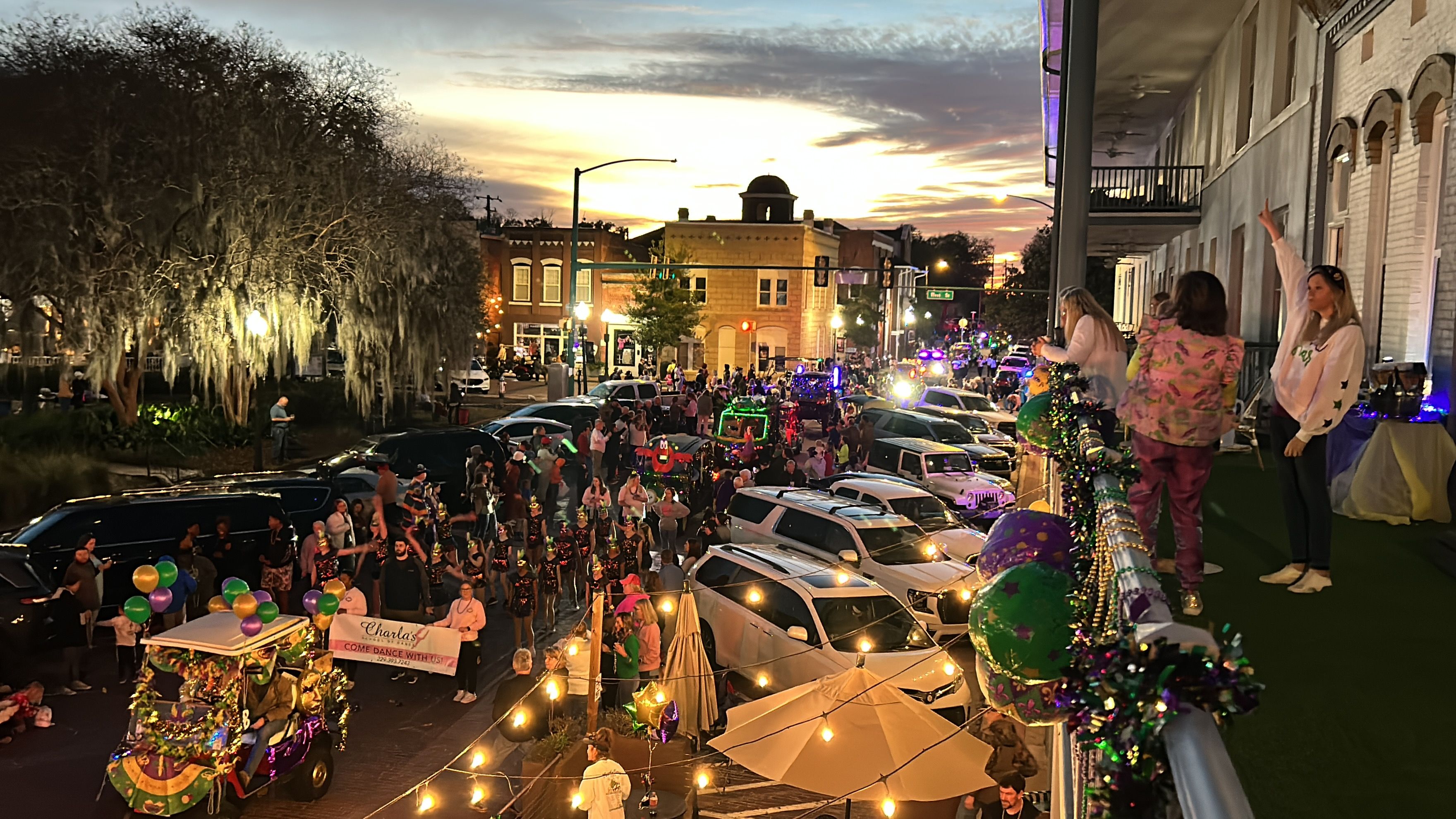 A crowded street scene with parked cars and a festive atmosphere.