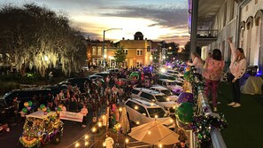 A crowded street scene with parked cars and a festive atmosphere.