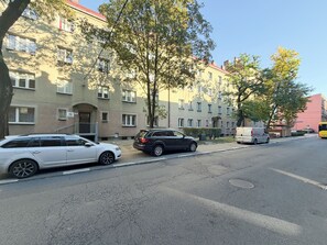 A street with parked cars, a bus, and multi-story buildings with balconies. - Bogedaina Central Apartment (Chorzów)