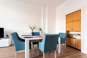 A modern dining area with a wooden cabinet, a television, and a table with chairs. - Plac Solidarności Spacious Apartment (Gdańsk)