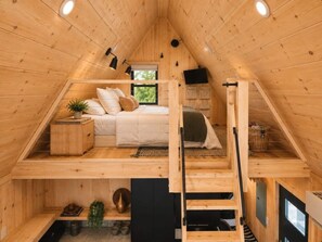 Ein Schlafzimmer im Loft-Stil mit einem Bett, einem kleinen Tisch und einem Fenster.