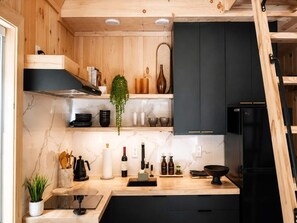 Eine moderne Küche mit Holzschränken, einem schwarzen Kühlschrank und einer Marmorarbeitsplatte.