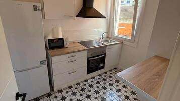 Cocina compacta con microondas, lavamanos y estufa.