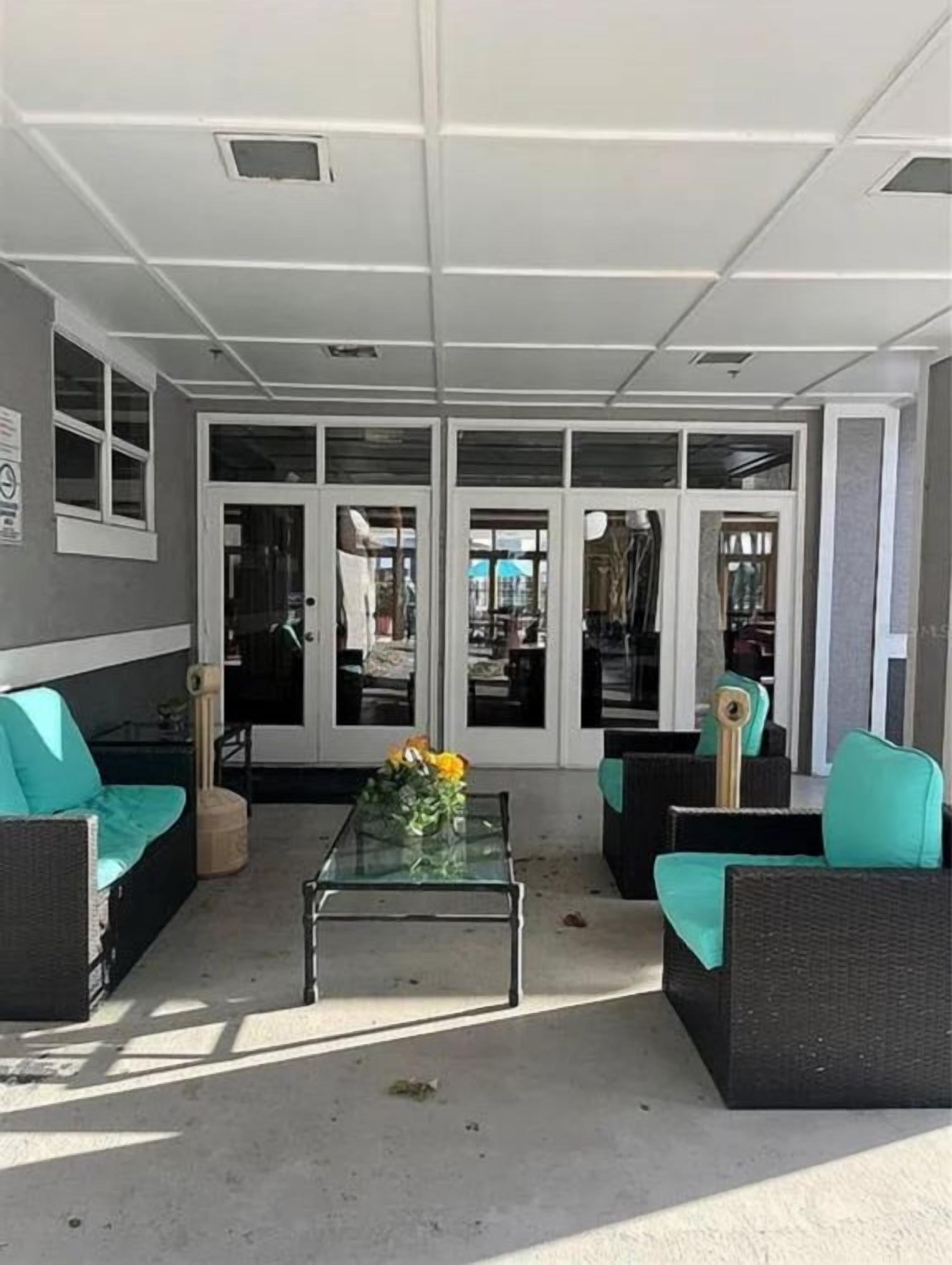 A welcoming outdoor lounge area greets you with comfortable wicker seating and pops of turquoise cushions. Relax here before or after exploring—your perfect spot to unwind just steps from your rental.