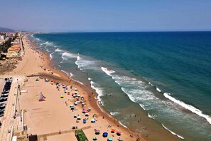 A beach with a long stretch of sand, a few umbrellas, and a clear view of the ocean. - Apartment with pool, 300 m from Piles beach (Piles)