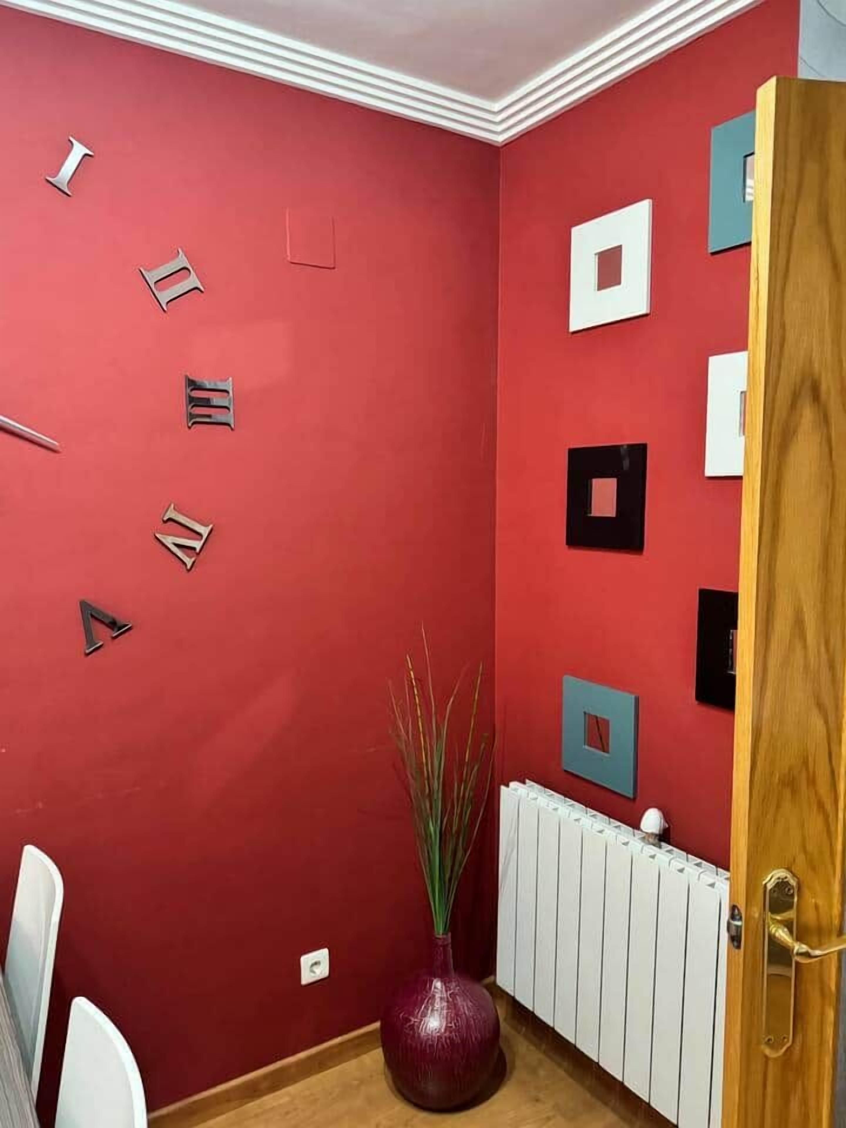Une pièce aux murs rouges, avec un radiateur blanc et une porte en bois.
