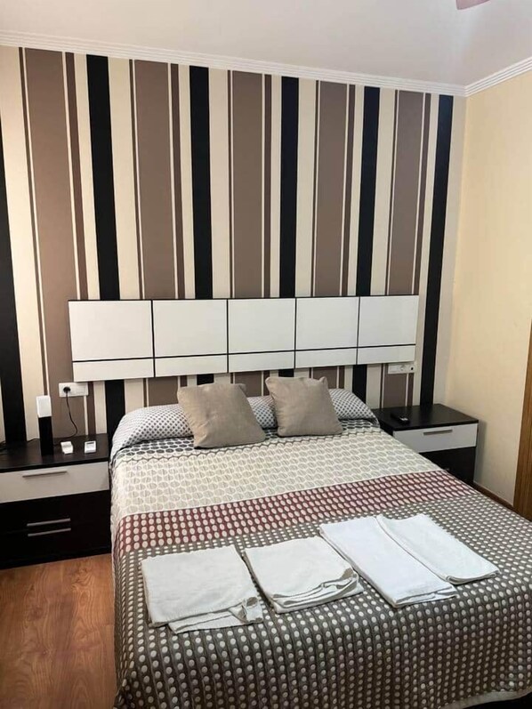 Een netjes ingerichte hotelkamer met een groot bed, een nachtkastje met een lamp, en een muur met verticale strepen.