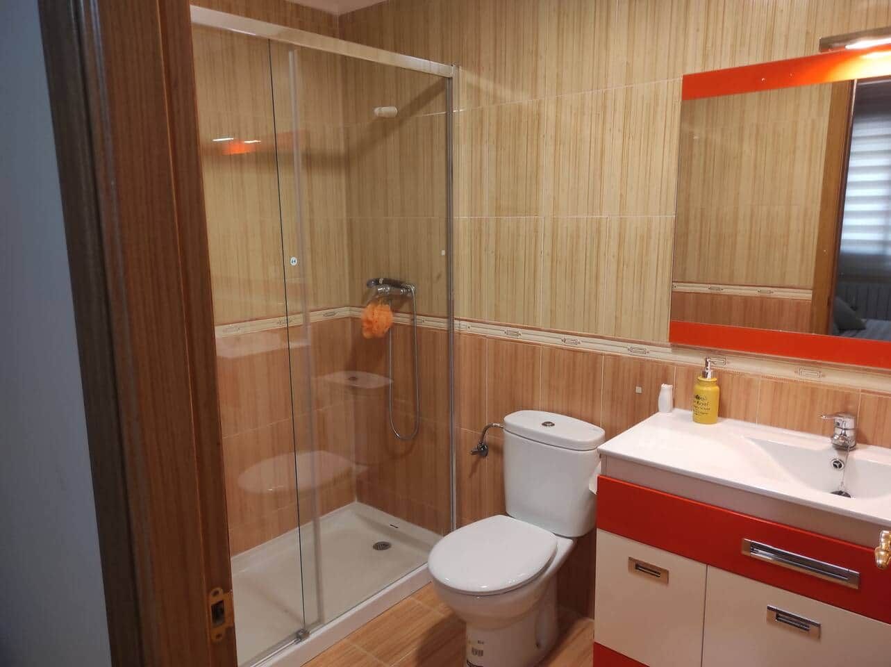 Een badkamer met een glazen douchecabine, een wit toilet en een wastafel met spiegel.