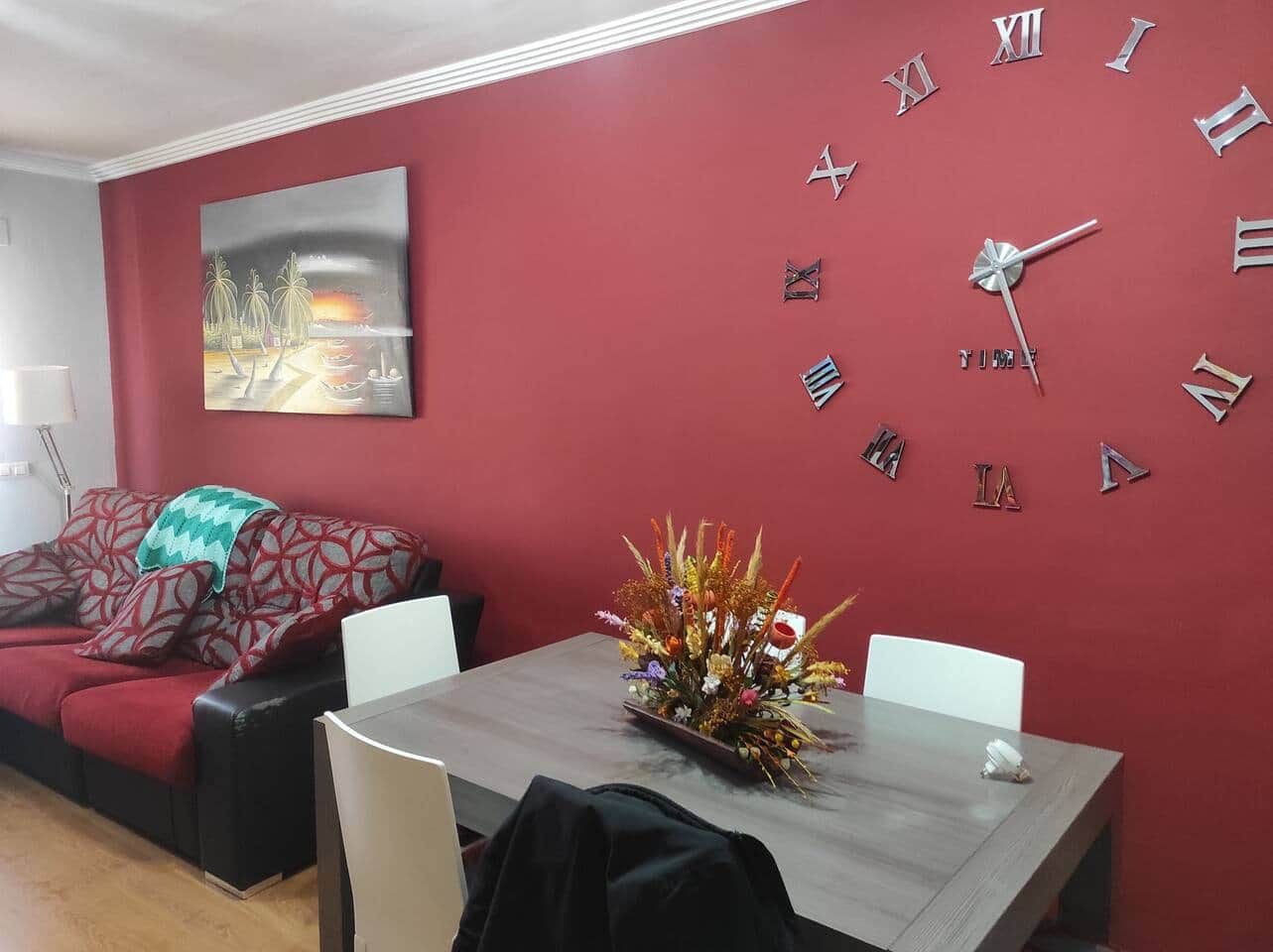 Ein Essbereich mit roter Wand, einer Uhr und einer floralen Tischdekoration.