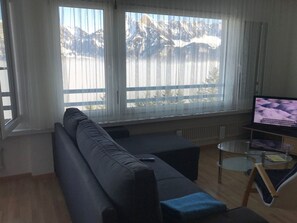 A living room with a sofa, a coffee table, and a TV. - Gauenpark (Whg. Uehli), (Flumserberg Tannenheim), by Interhome (Flumserberg Tannenheim)