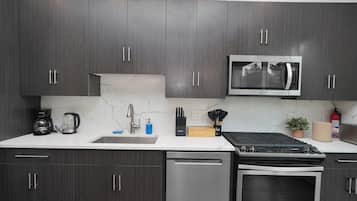 A modern kitchen with dark wood cabinets, a stainless steel microwave, a coffee maker, and a dishwasher.