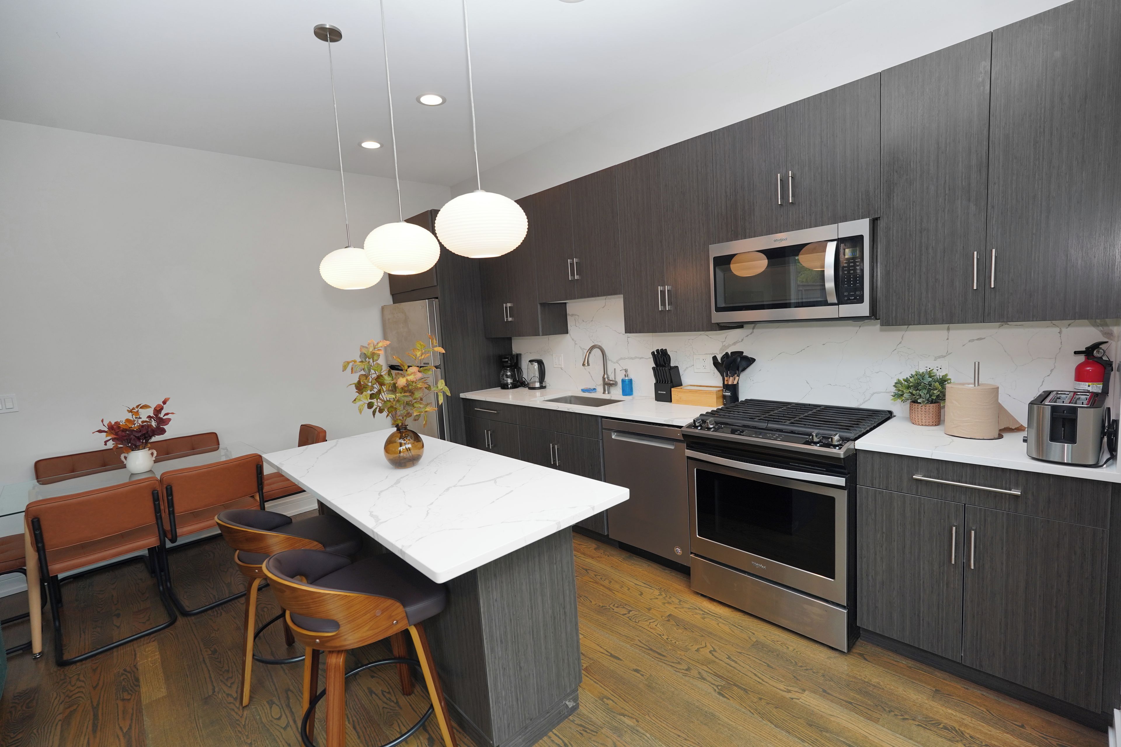 A modern kitchen with dark wood cabinets, stainless steel appliances, and a marble countertop.