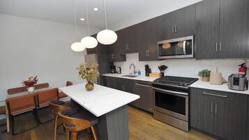 A modern kitchen with dark wood cabinets, stainless steel appliances, and a marble countertop.