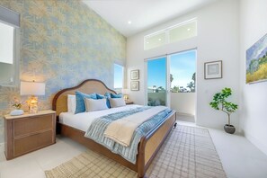 A bedroom with a large bed, nightstands, a potted plant, and a view of the outdoors through a sliding door. - Sunset House - Rooftop Ocean & Bay Views (San Diego)