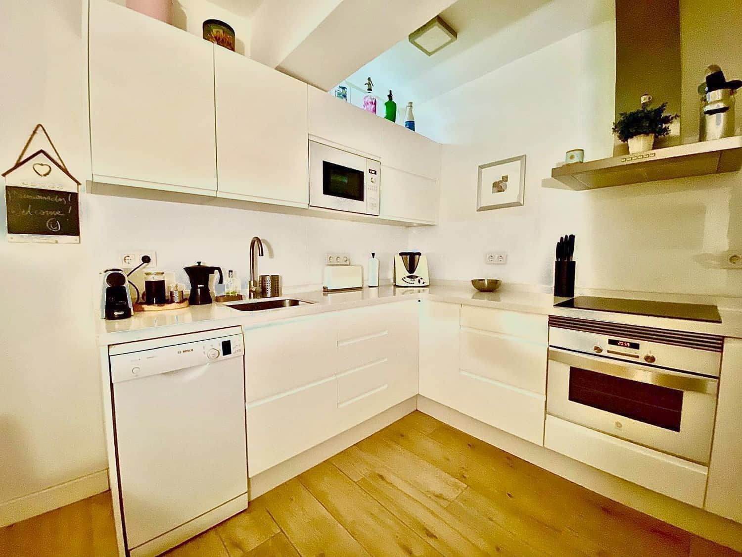 A modern kitchen with white cabinetry, a microwave, a dishwasher, and a stove.