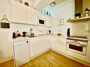 A modern kitchen with white cabinetry, a microwave, a dishwasher, and a stove. - Renovated 3-bedroom apartment · Conde de Ureña, Málaga (Málaga)