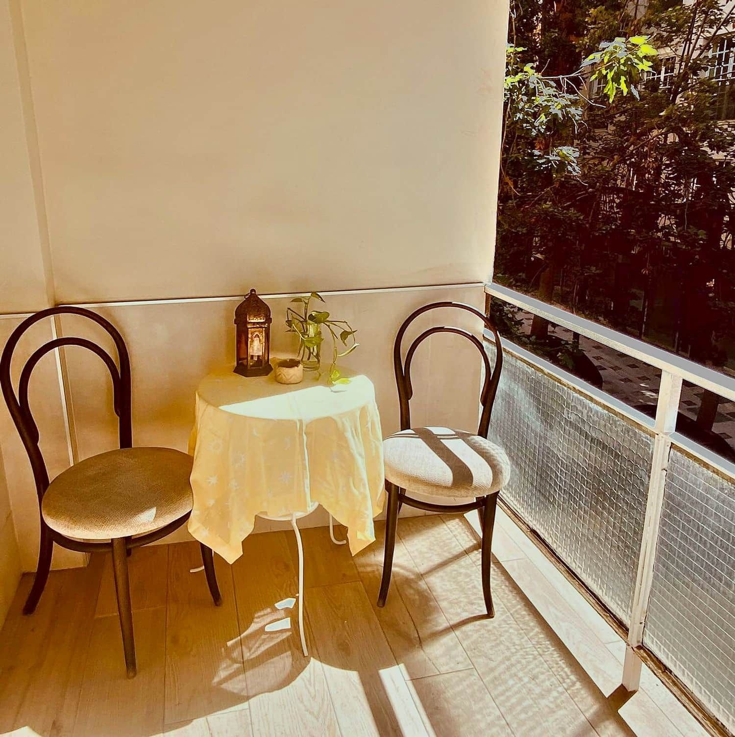 A balcony with two chairs, a small table, and a lantern.