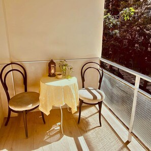 A balcony with two chairs, a small table, and a lantern. - Renovated 3-bedroom apartment · Conde de Ureña, Málaga (Málaga)