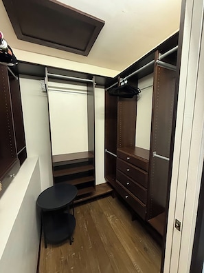 A walk-in closet with a mirror, a hanging rod, and a small table. - Presidential Two Bedroom, Two Bath Suite (San Luis Obispo)