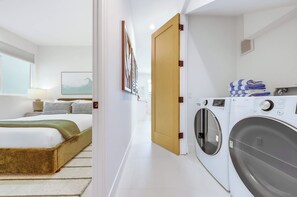 Ein Hotelzimmer mit einem Bett, einer Waschmaschine und einer Tür zu einem anderen Raum.