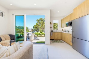 A modern apartment with a living room, a kitchen, and a balcony with a view of the city. - The Haines House - Pacific Beach (San Diego)