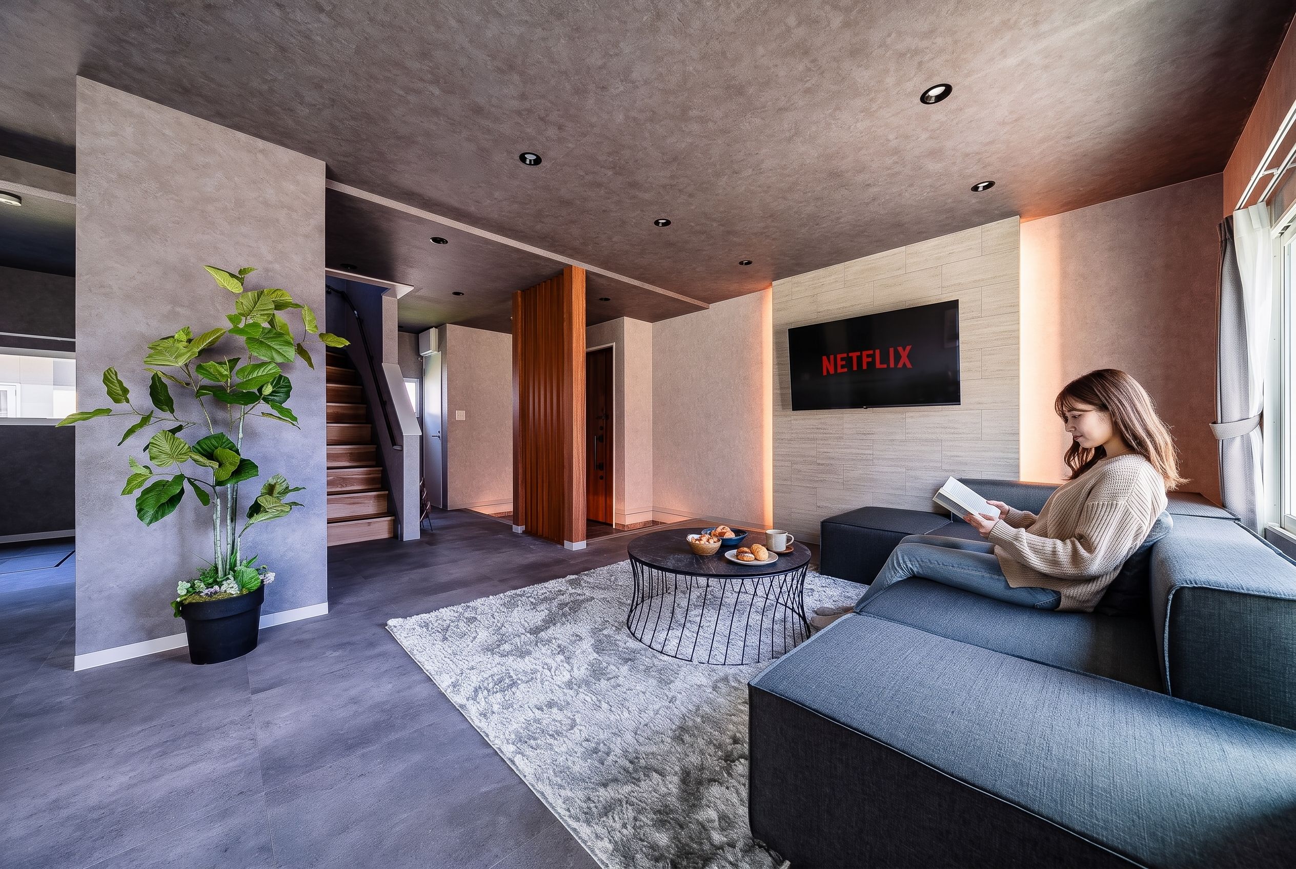 A modern living room with a sofa, a coffee table, and a large TV screen displaying the Netflix logo.