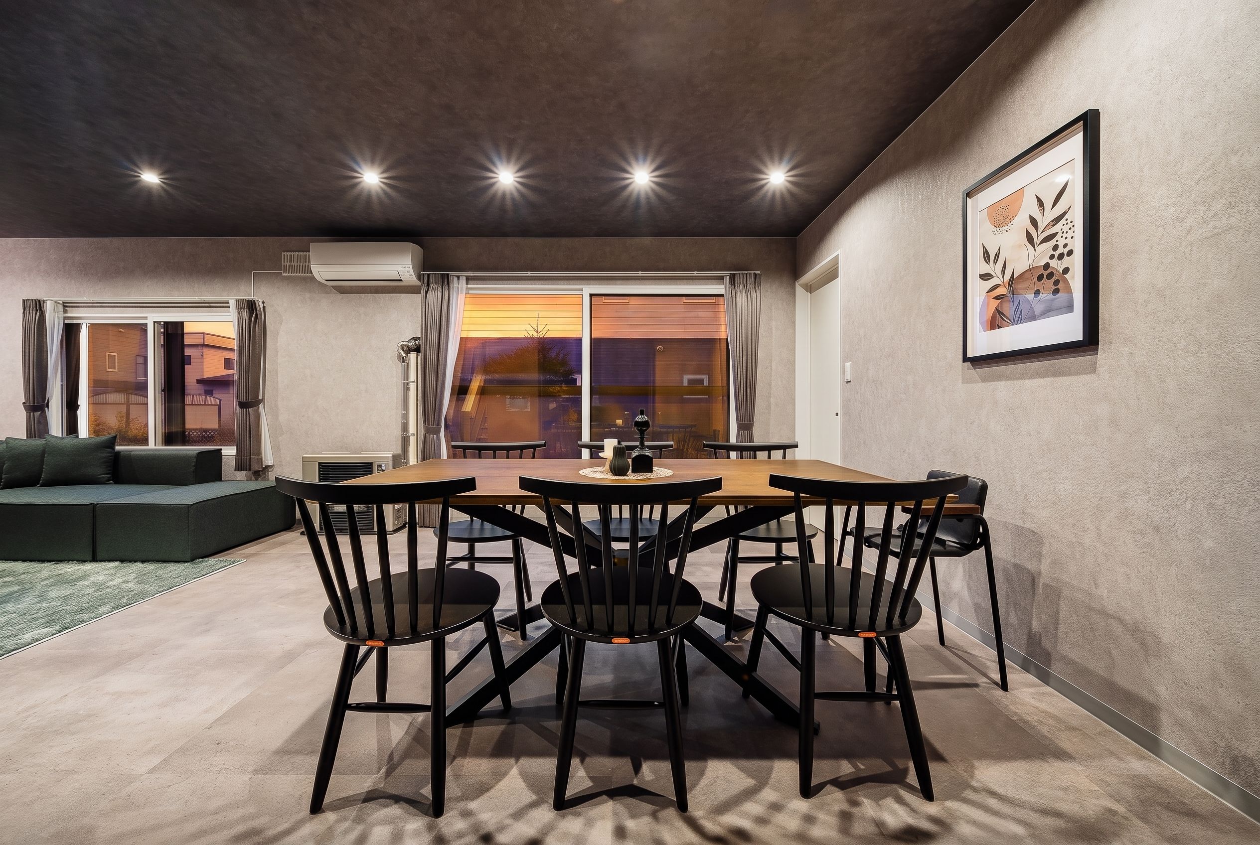 Un área de comedor con una mesa y sillas, un sofá y un ventanal con vistas.