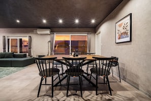 Un área de comedor con una mesa y sillas, un sofá y un ventanal con vistas.