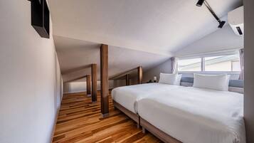 Una habitación de hotel moderna con una cama grande, suelo de madera y una lámpara fijada al techo.