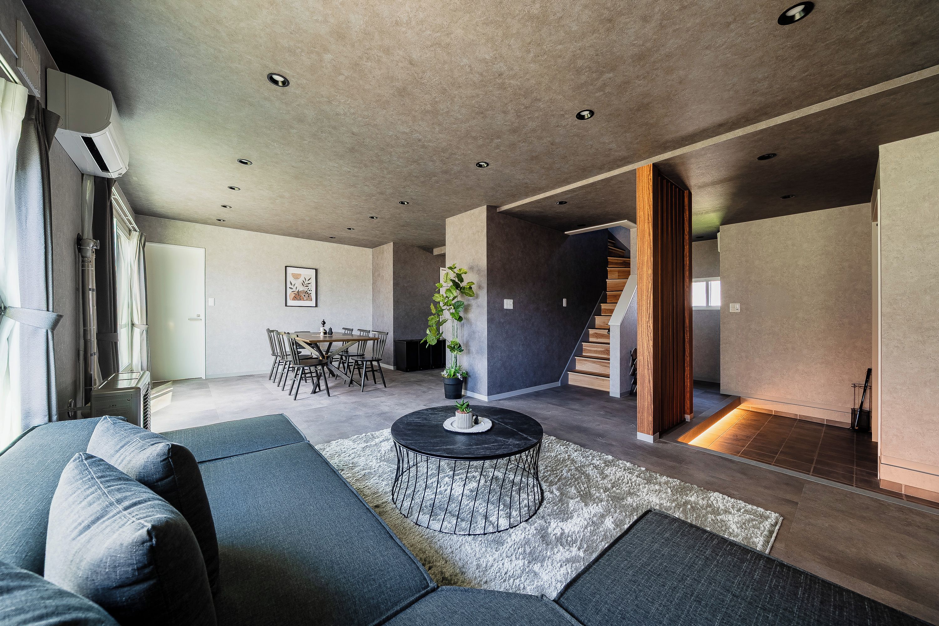 A modern living room with a sectional sofa, a round coffee table, and a dining area with chairs and a table.