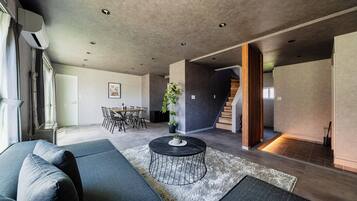 A modern living room with a sectional sofa, a round coffee table, and a dining area with chairs and a table.