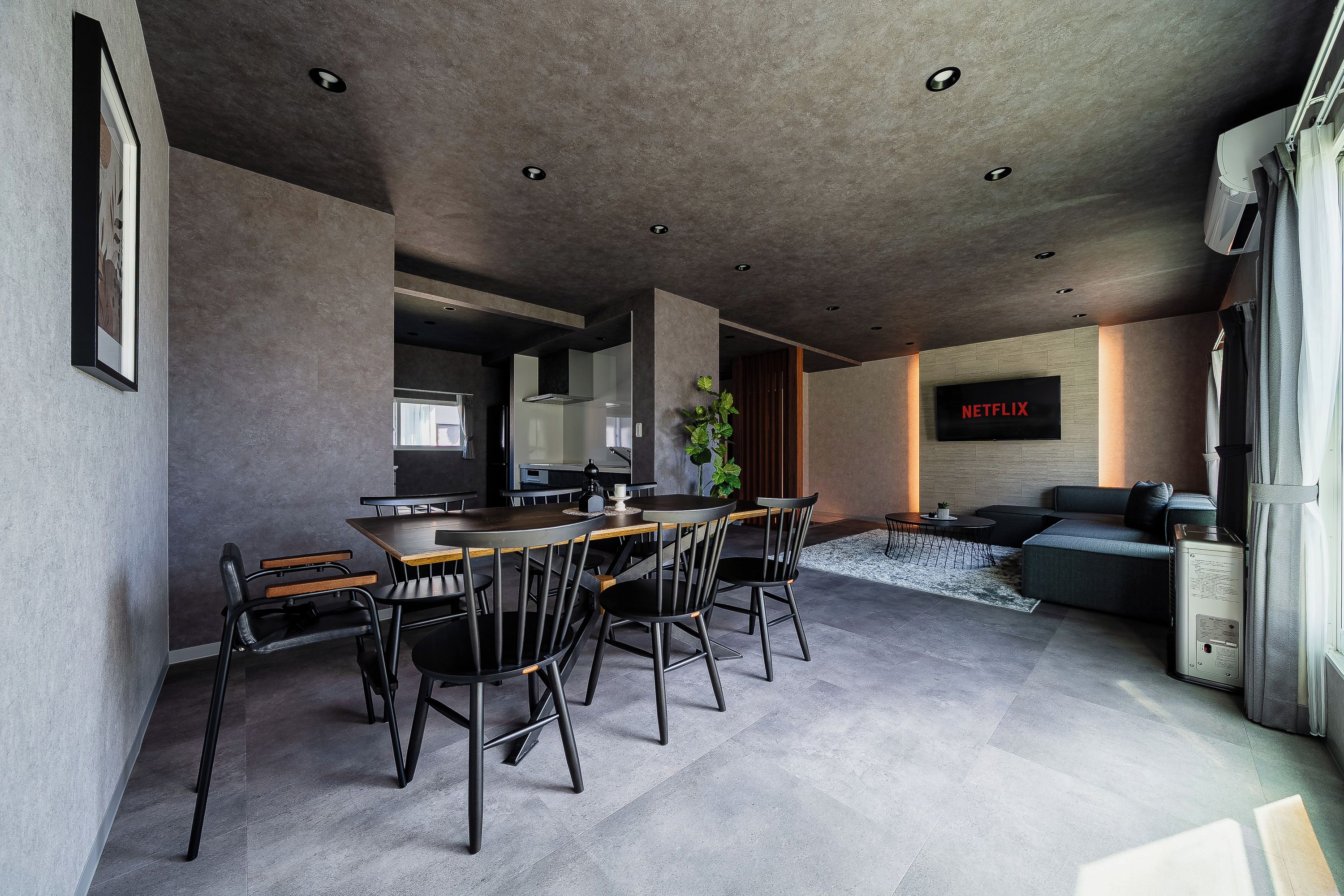 A modern interior with a dining area, seating, and a flat-screen TV displaying 'NETFLIX'.