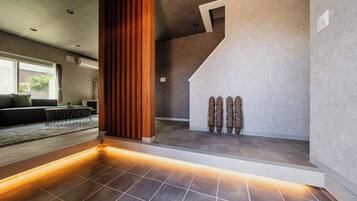A modern interior with a staircase, a seating area with a sofa and table, and a shoe rack.
