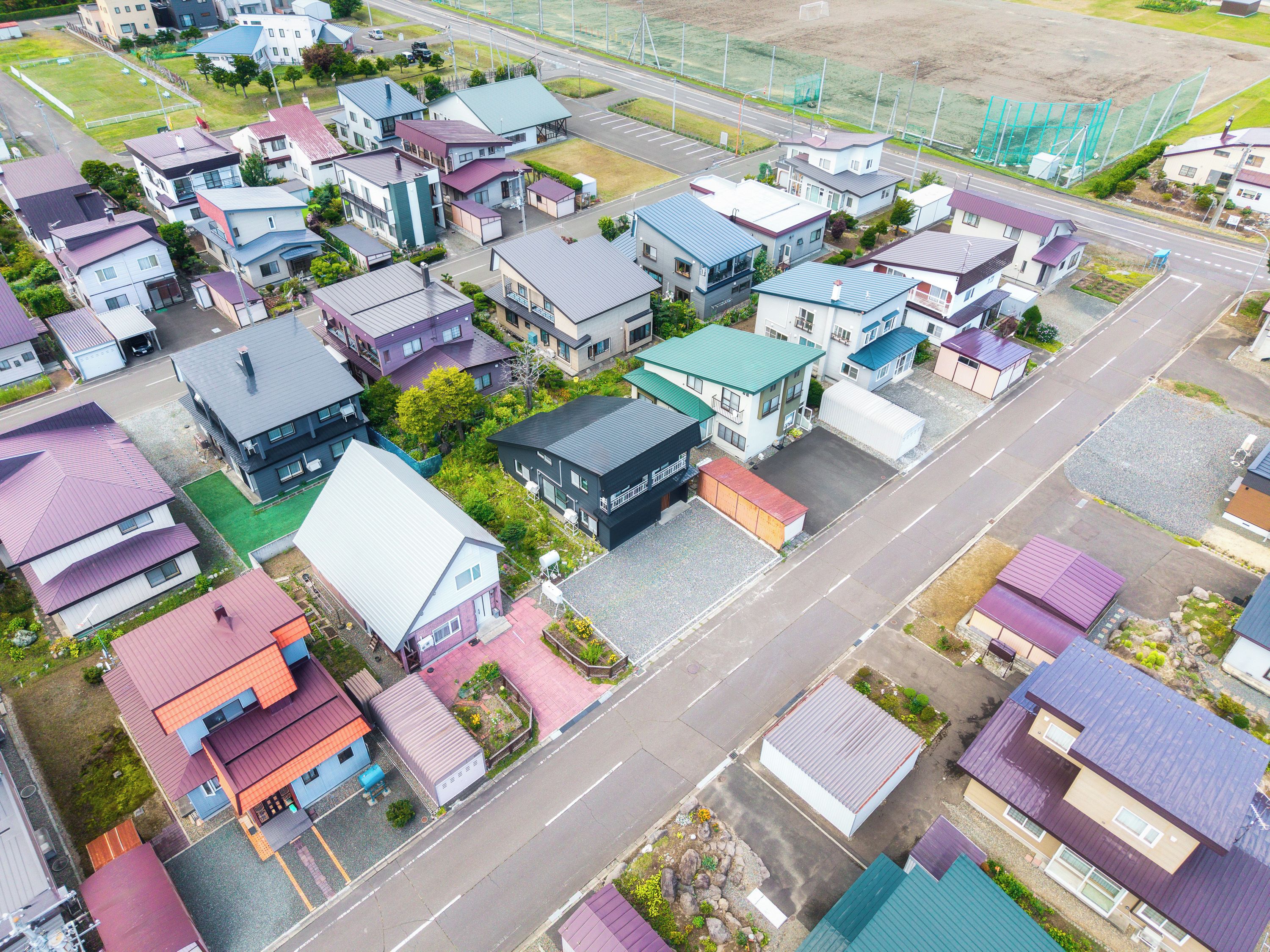Zona residencial con casas de diferentes tamaños y diseños, una avenida principal y un campo deportivo.