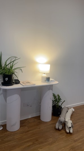 A corner of a room with a white console table, a lamp, a potted plant, and a plush toy on the floor. - Relax recharge ! (Clontarf)