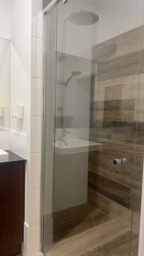 A glass-enclosed shower with a handheld showerhead and a wall-mounted faucet. - Relax recharge ! (Clontarf)