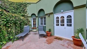 Ein Innenhof mit zwei Liegestühlen, einem kleinen Tisch und Kübelpflanzen.