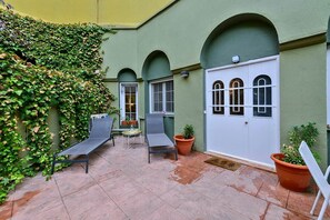 Ein Innenhof mit zwei Liegestühlen, einem kleinen Tisch und Kübelpflanzen.