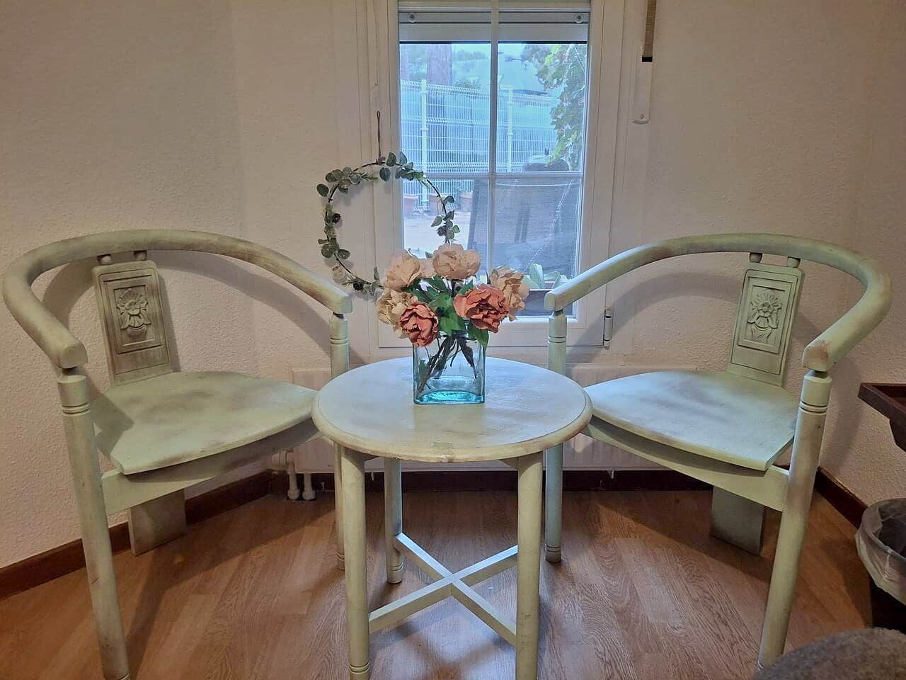 A room with a round table and two chairs with decorative elements.