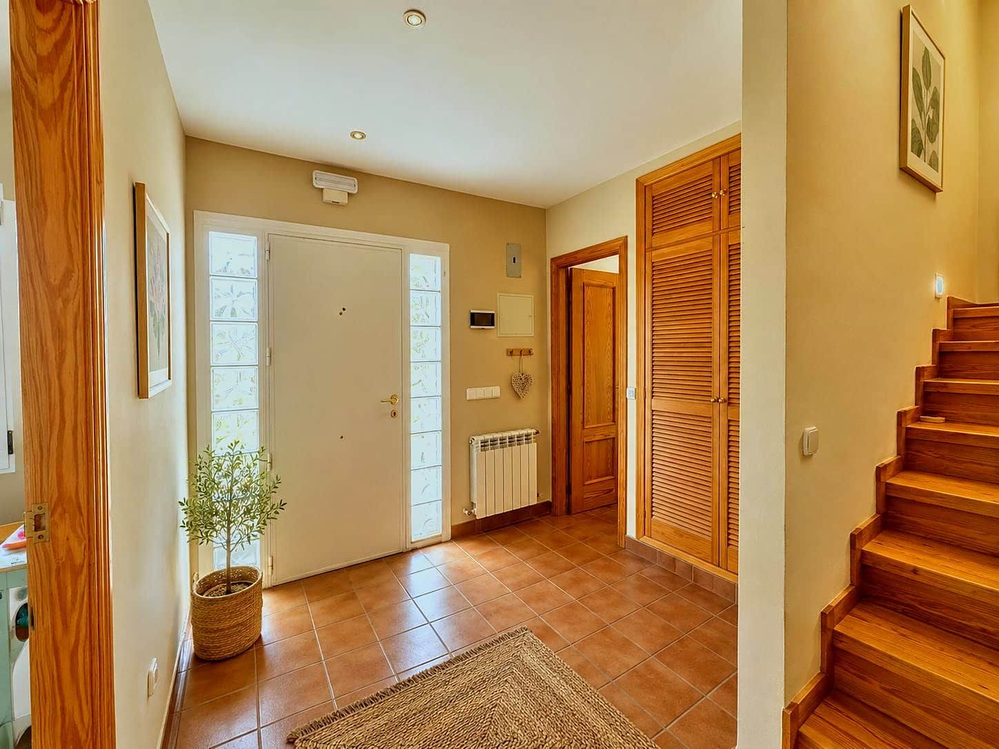 Un couloir avec une porte en bois, un radiateur, une plante en pot et un escalier.