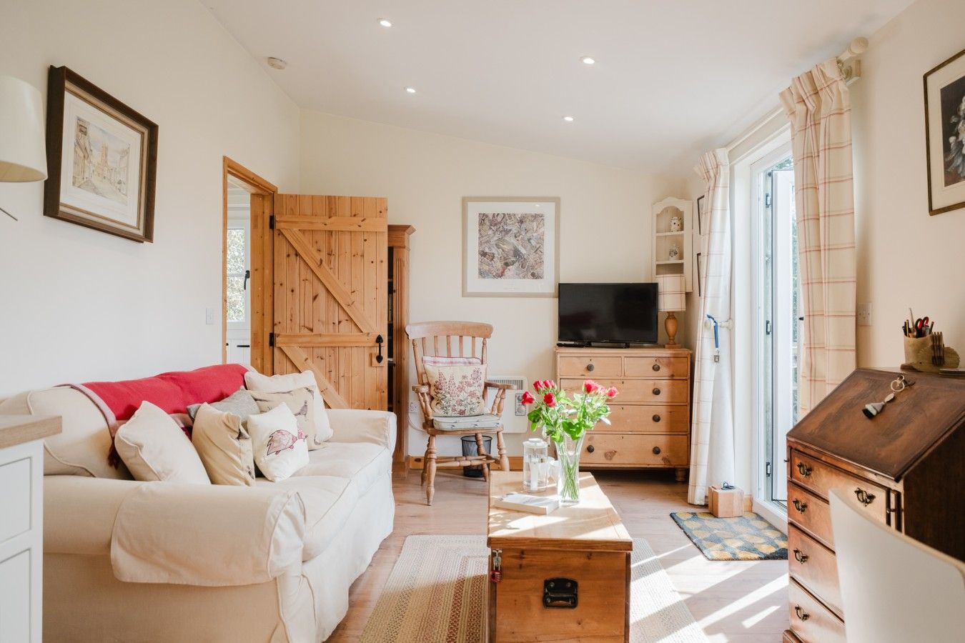 A cozy living room with a sofa, a wooden cabinet, a television, and a door leading to another room.