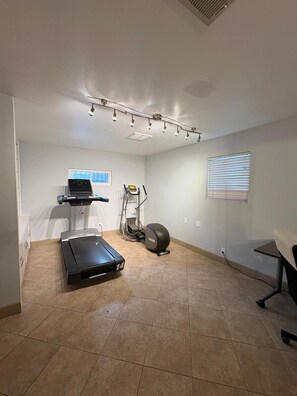 Une salle de sport à domicile équipée d’un tapis de course, d’un vélo elliptique et d’un vélo d’appartement.