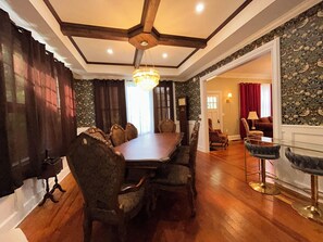 A dining area with a wooden table and chairs, a chandelier, and a clock on the wall. - Historic Fleming House, 4BR 3BA, Sleeps 8-10, 3-5 Min Walk to Square (Bainbridge)