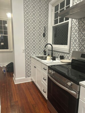 A kitchen with a black stove, white cabinets, and a patterned backsplash. - Historic Fleming House, 4BR 3BA, Sleeps 8-10, 3-5 Min Walk to Square (Bainbridge)