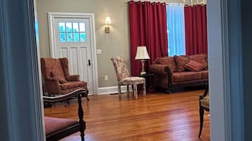 A living room with hardwood flooring, a door, a red curtain, and two lamps.