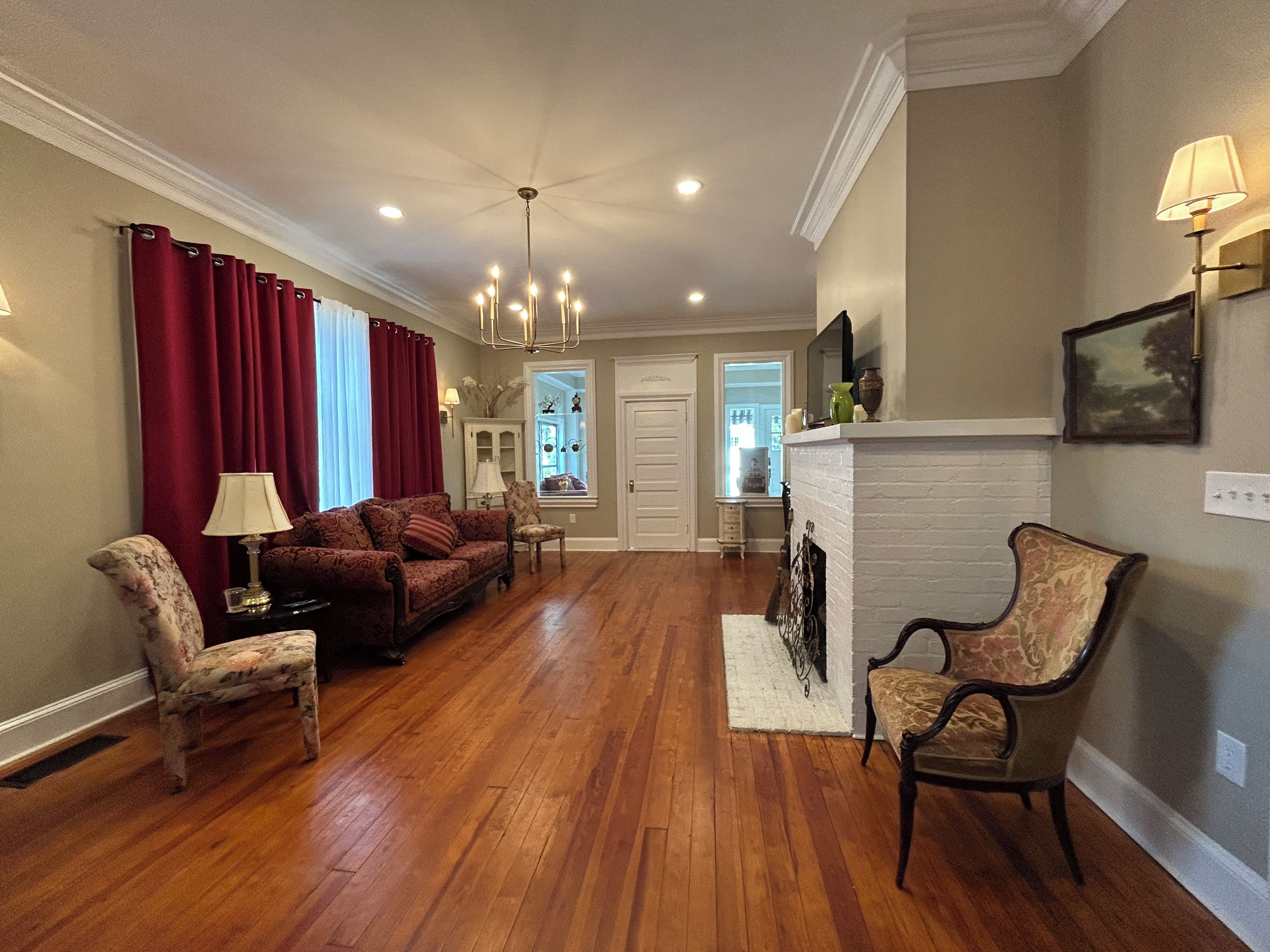 A spacious living room with hardwood flooring, a fireplace, and a seating area with a sofa and chairs.