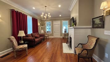 A spacious living room with hardwood flooring, a fireplace, and a seating area with a sofa and chairs.